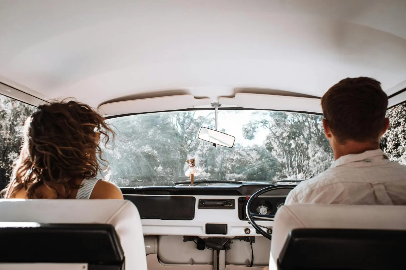 Imagen de un hombre y una mujer dentro de un coche blanco en la naturaleza